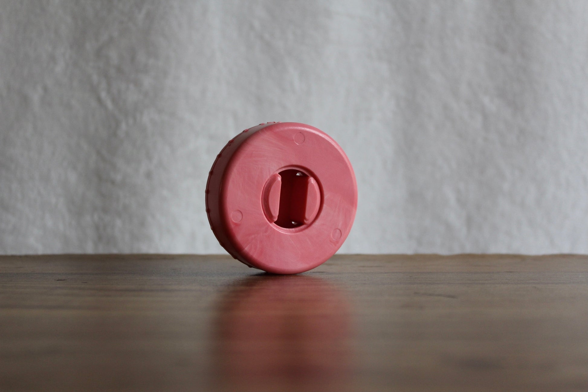 Pink-colored CordPuck cord organizer